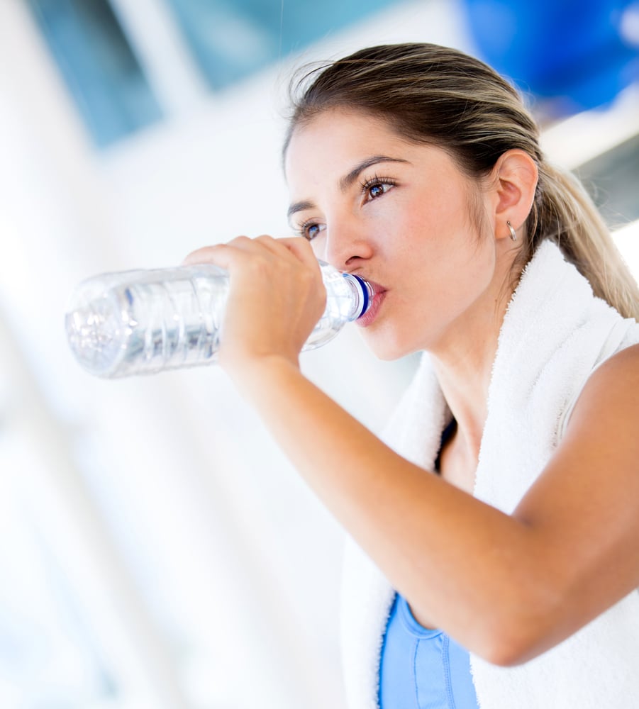Woman drinking water at the gym after working out Woman drinking water at the gym after working out